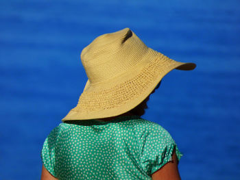 Rear view of woman wearing sun hat against blue sea on sunny day