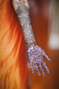 Midsection of woman with henna tattoo on hand 