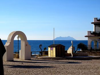 Buildings by sea against blue sky