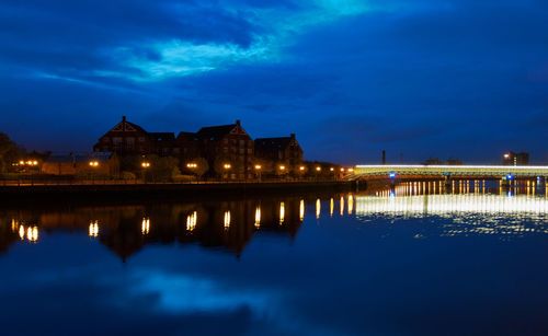 Illuminated bridge over river against sky at dusk