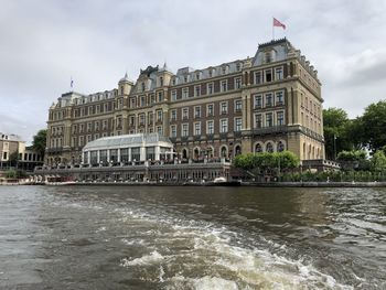 View of building by river against cloudy sky