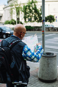 Rear view of man reading map on footpath