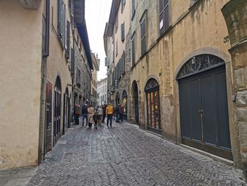 People walking on footpath amidst buildings in city