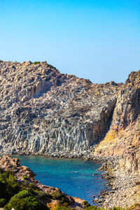 Scenic view of sea and rocks against clear blue sky