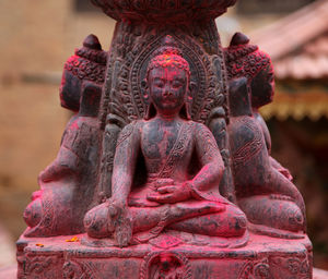 Close-up of buddha statues covered with sindoor at temple