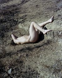 Low section of woman relaxing on sand at beach