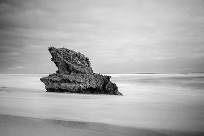 Rock formation amidst sea against sky