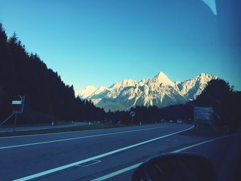 Road leading towards mountains against blue sky