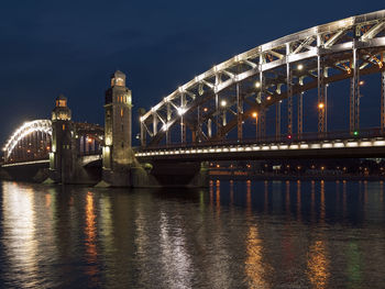 Illuminated bridge over river at night