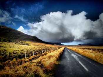 Road amidst field against sky