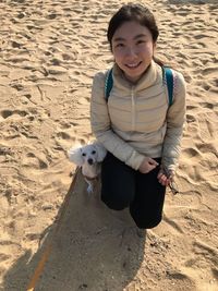 Portrait of happy boy with dog on sand at beach