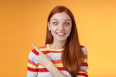 Portrait of smiling young woman against gray background