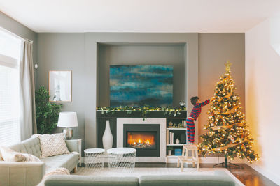 Side view of boy decorating christmas tree at home