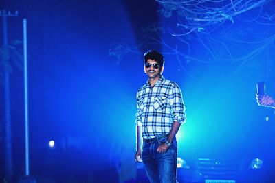 Portrait of man wearing sunglasses standing outdoors at night