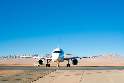 Airplane on airport runway against clear blue sky