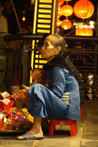 Woman looking away while sitting at market stall