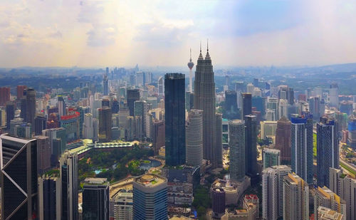 Aerial view of city buildings against cloudy sky