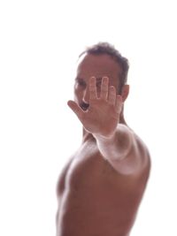 Portrait of shirtless man gesturing stop sign against white background