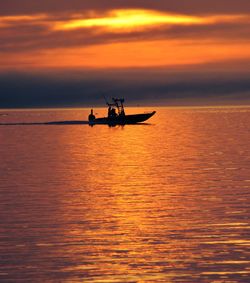 Silhouette man in boat on sea against sky during sunset