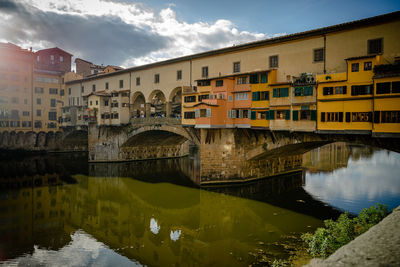 Bridge over river by buildings against sky in city, ponte vecchio florence italy