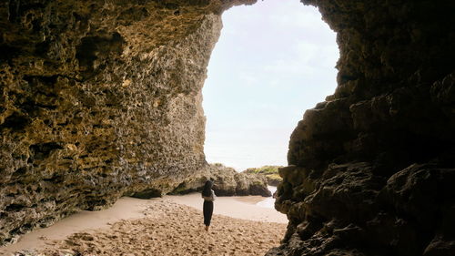 Woman standing on rock by sea against sky