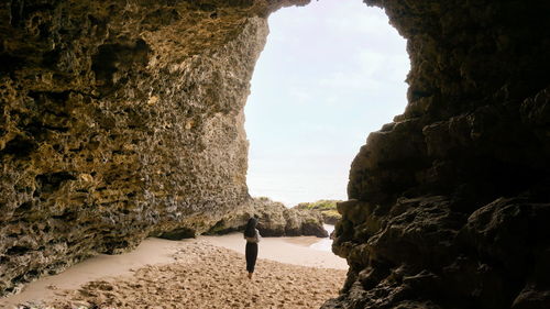 Woman standing on sand by sea against sky