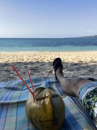 Man lying down on beach against clear sky