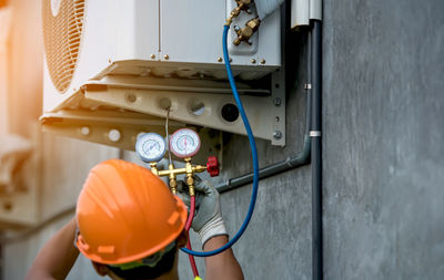 Rear view of manual worker examining air conditioner