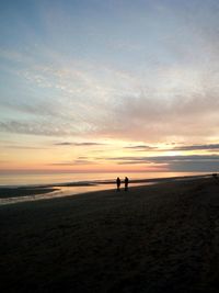 Silhouette couple at beach against sky during sunset