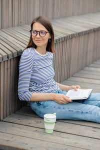 Woman reads a book and rests in a public place drinks coffee. european woman meditates in the park