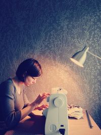 Woman using sewing machine at home