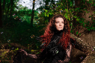 Portrait of beautiful young woman against trees