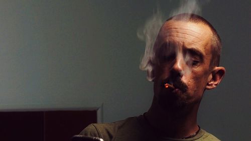 Close-up of man smoking cigarette at home