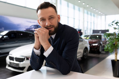 Salesman leaning on table in car showroom