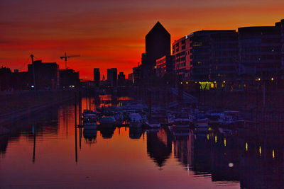 Reflection of illuminated buildings in lake during sunset