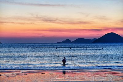 Silhouette person standing on beach against sky during sunset