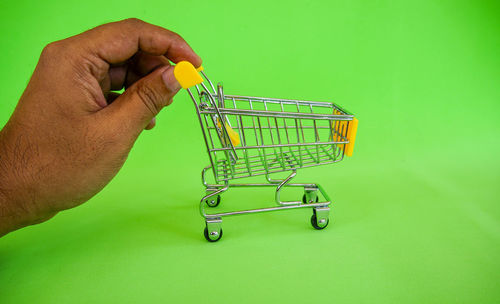 Cropped image of man holding metallic structure against green background