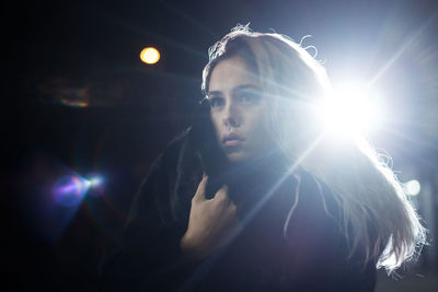 Close-up of young woman standing against sky at night