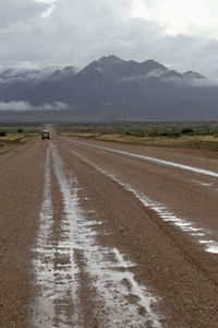 Scenic view of road by land and mountains against sky