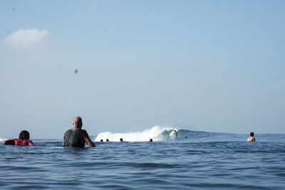 People surfing in  bali against sky