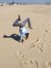 High angle view of woman doing handstand on sand at beach