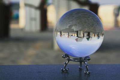 Close-up of crystal ball on glass against building in city