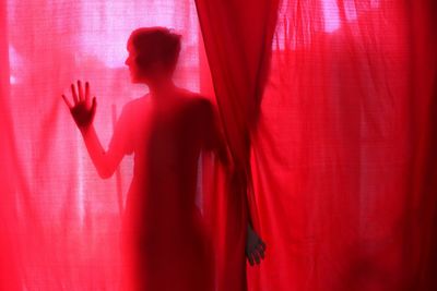 Close-up of hands against red curtain