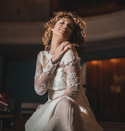 Portrait of young woman in dress sitting on piano