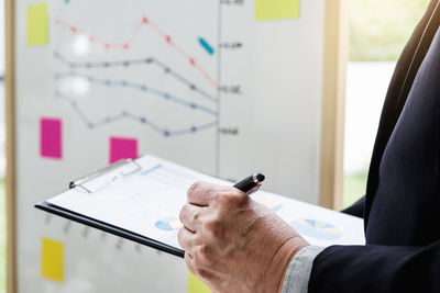 Midsection of businessman working on graph at office