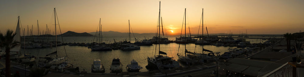 Sailboats moored at harbor during sunset