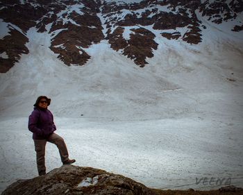 Full length of woman standing on rock during winter