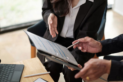 Midsection of couple holding hands on paper