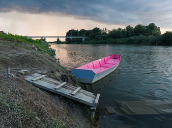 Boat moored on river against sky