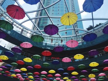 Low angle view of multi colored umbrellas hanging against sky